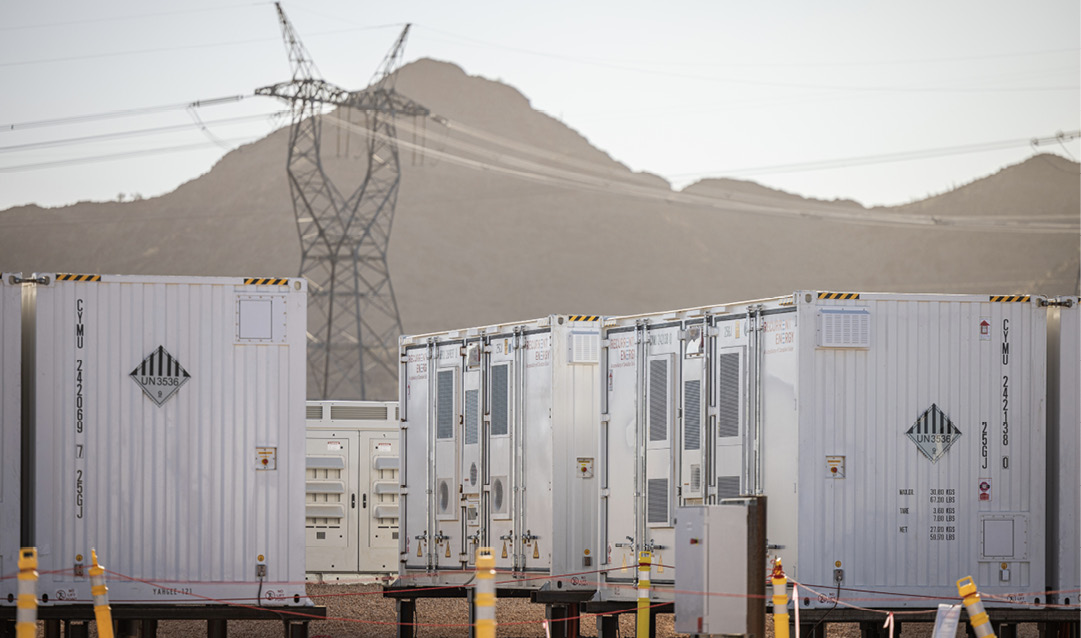 Battery containers with electricity pylons and mountains in the background.