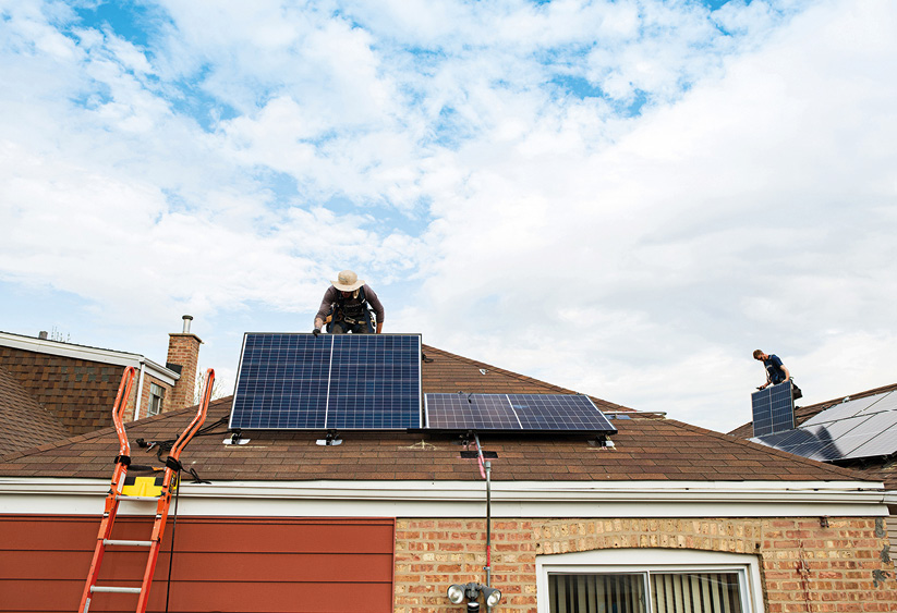 Installers place PV panels on a roof.