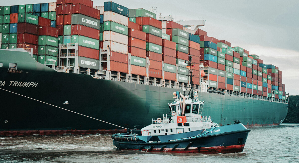 A container ship being towed into port.